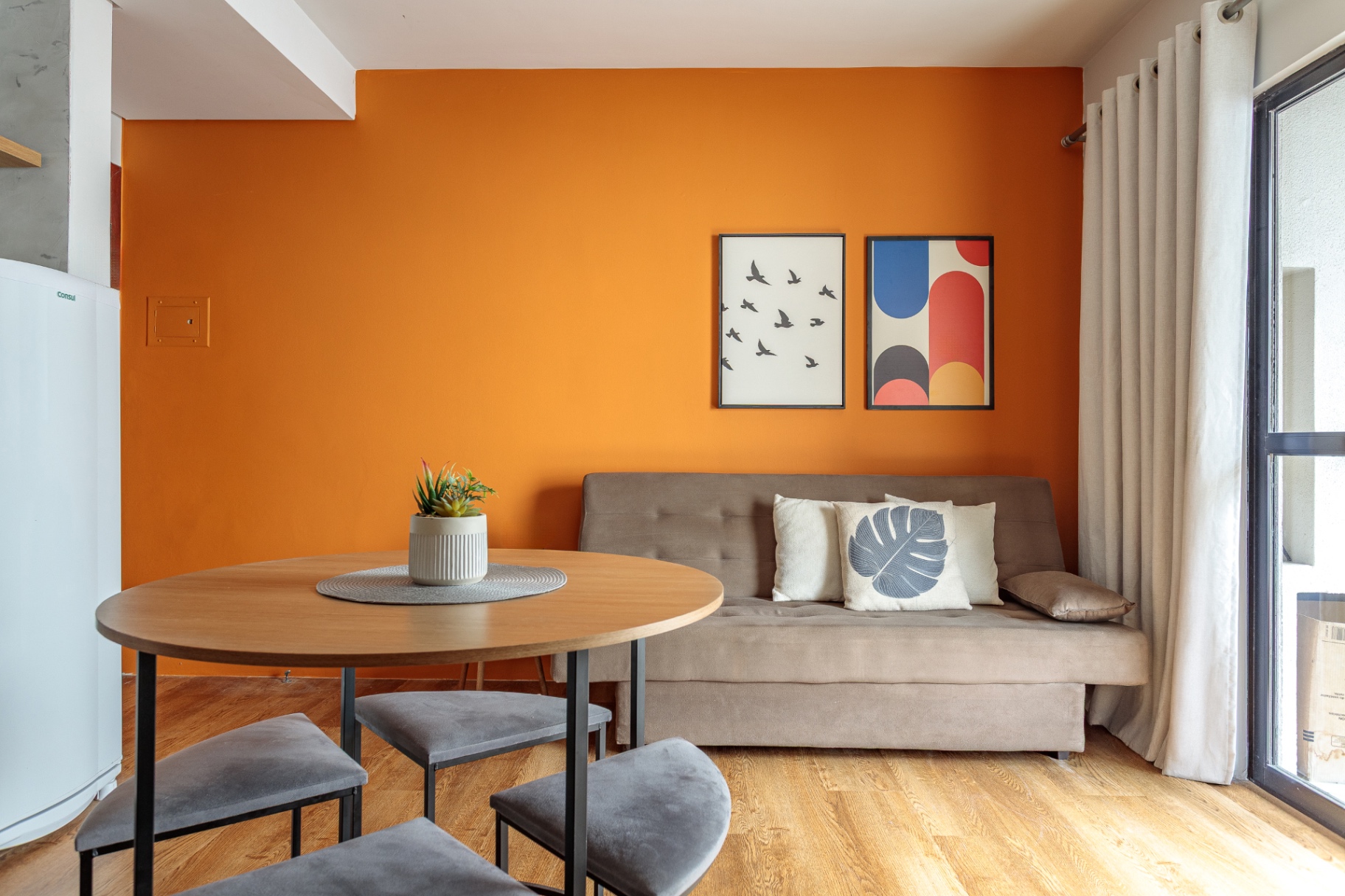 Sala de estar do Apartamento 102 com parede laranja e quadros